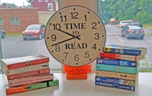 image of a clock on a table, surrounded by books